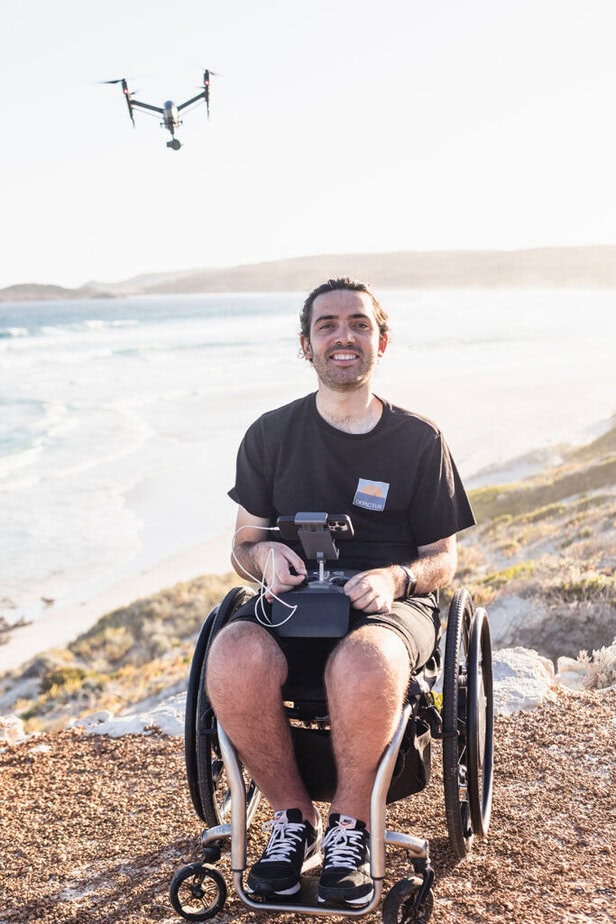 Man in wheelchair with drone above him and controller in his lap