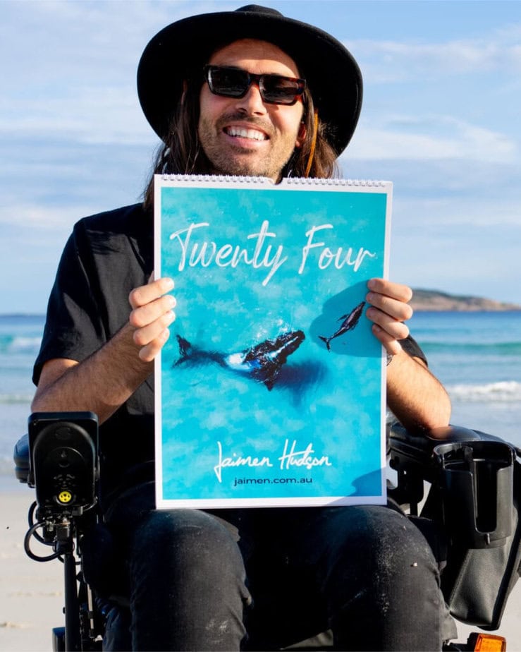 Man in wheelchair holding up large wall calendar