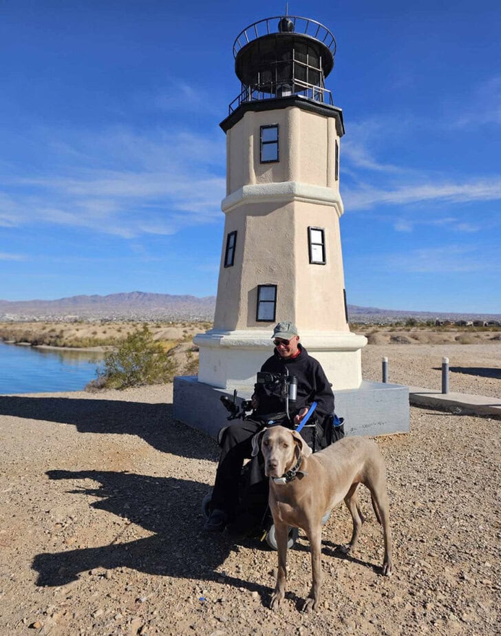 man in wheelchair pictured with dog in front of Lake Havasu lighthouse
