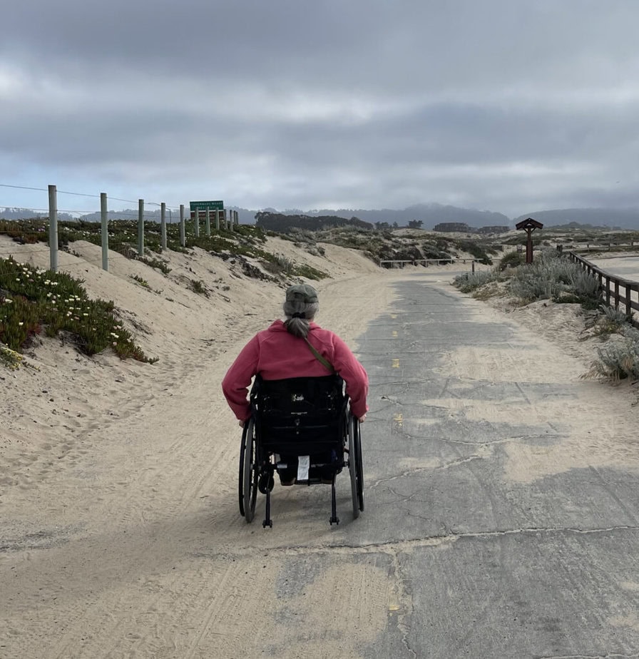 man wheeling away down a sandy beach side road