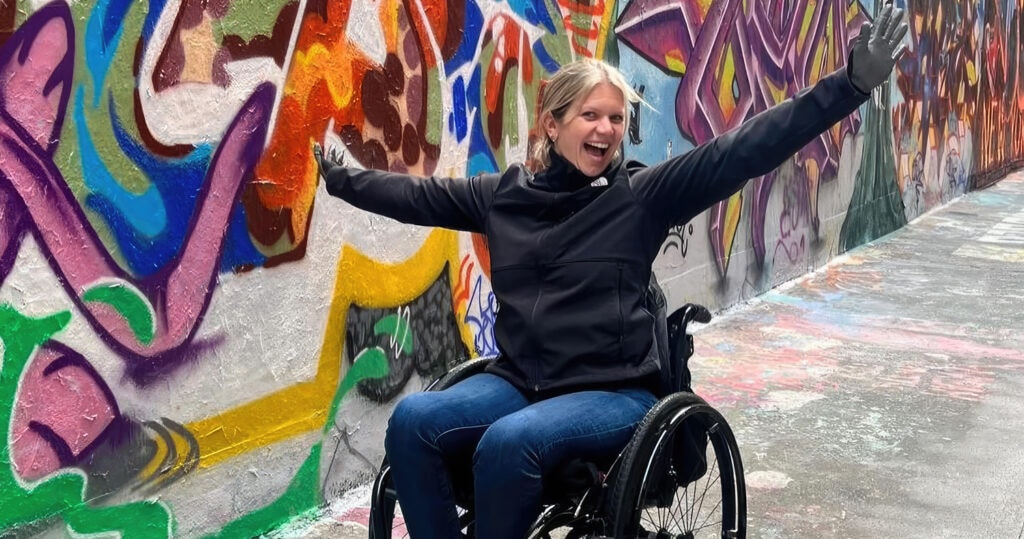 woman in wheelchair posing in front of graffiti art wall in NYC