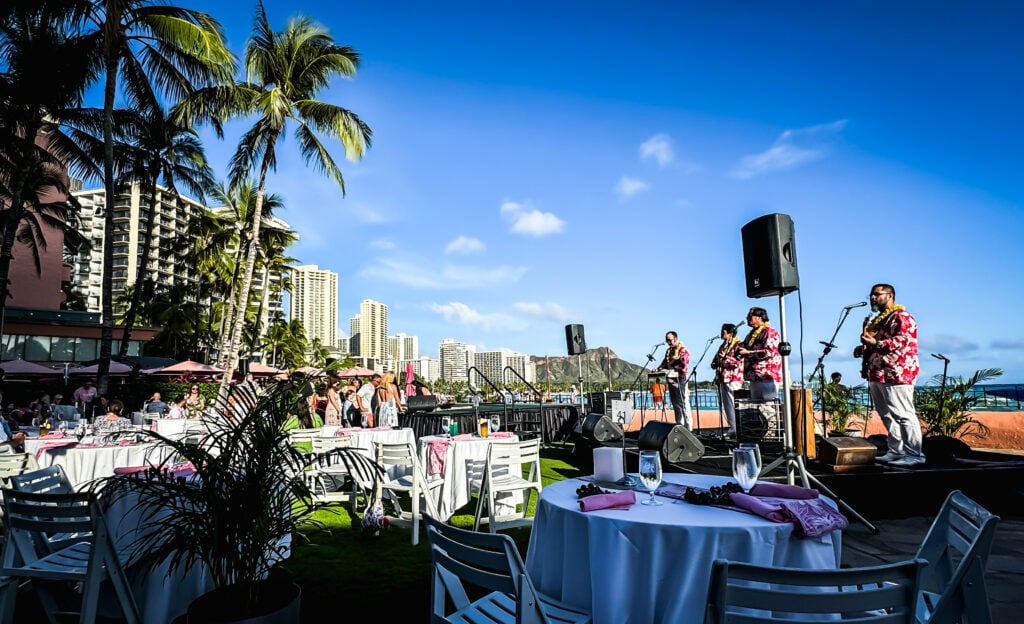 Hawaiin dancers at a Luau, palm trees in the background. 