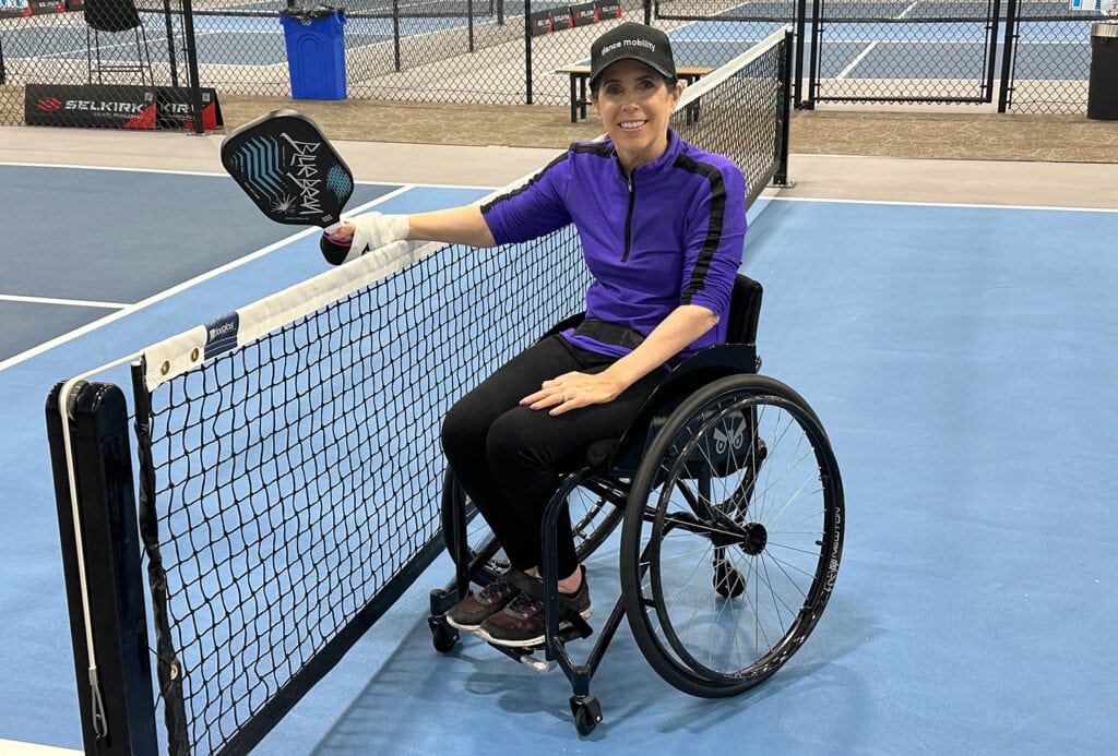 woman  in wheelchair at net on paddleboard court
