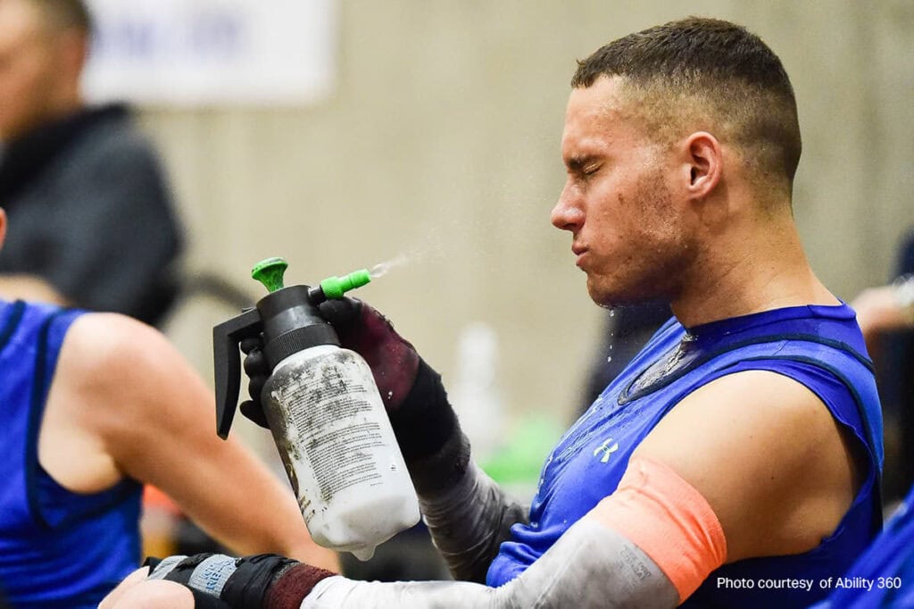 Man spraying himself with a garden mister. 