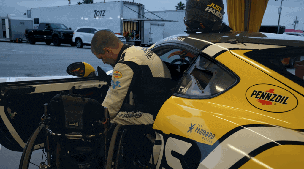 a male manual wheelchair user transfering into a yellow and black racing Porsche. 