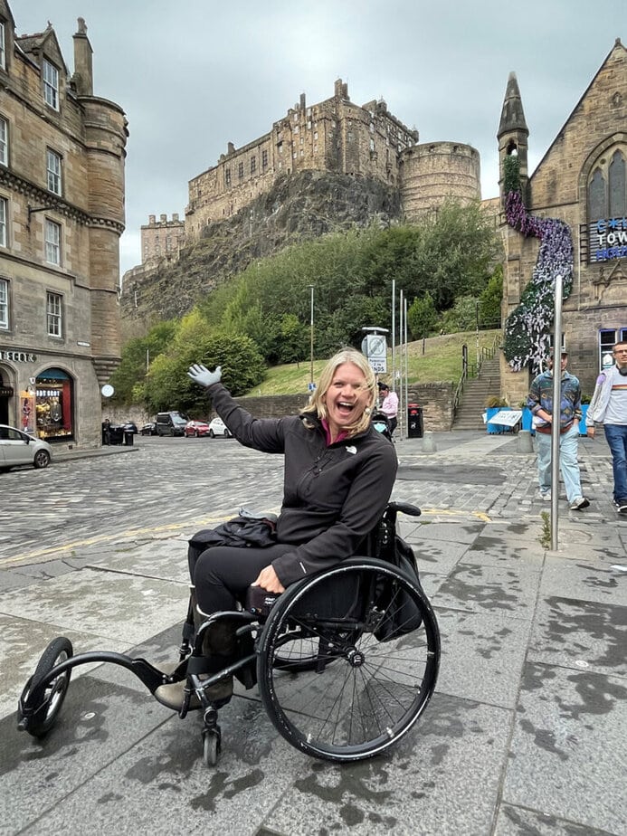 Wheelchair user enjoying historic Edinburgh castle view.