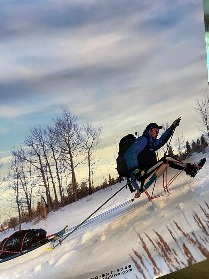 man XC skiing pulling a sled