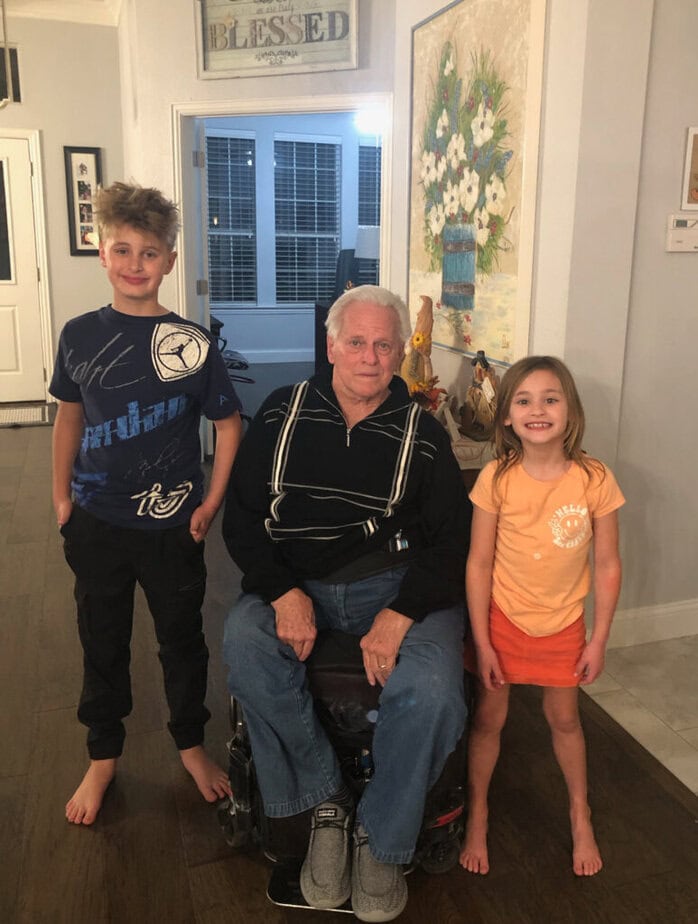 man in wheelchair picured between young boy and girl