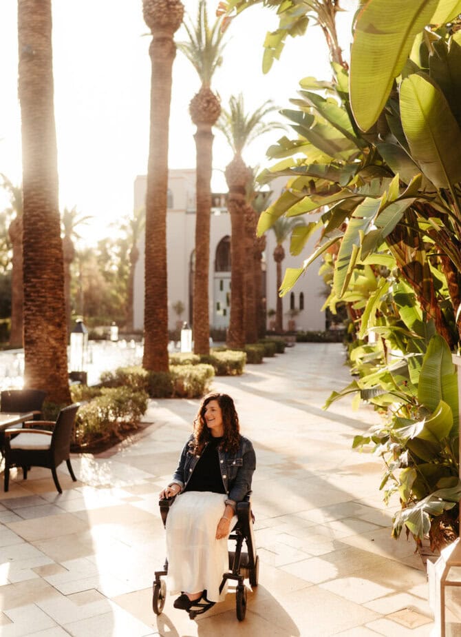 woman in wheelchair outside in hotel courtyard featuring palm trees