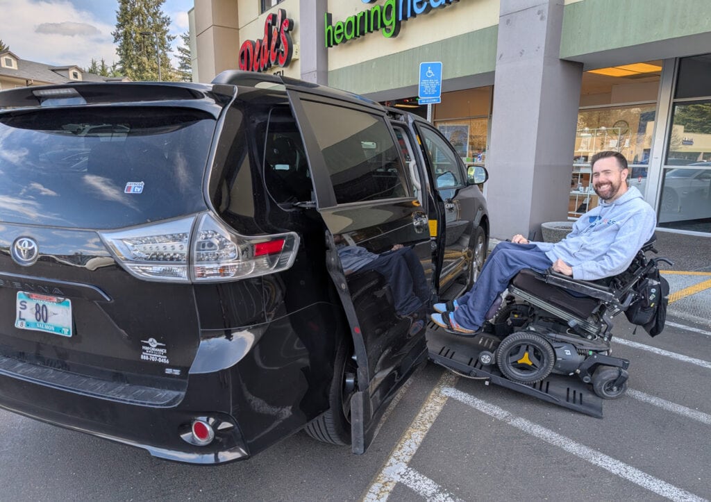 the author in powerchair going up van side ramp in  parking lot